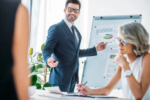 Homme d'affaires heureux pointant sur tableau à feuilles mobiles lors de la présentation au bureau — Photo de stock