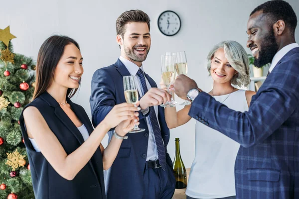 Uomini d'affari multiculturali che si agitano con bicchieri di champagne con albero di Natale sullo sfondo in ufficio — Foto stock