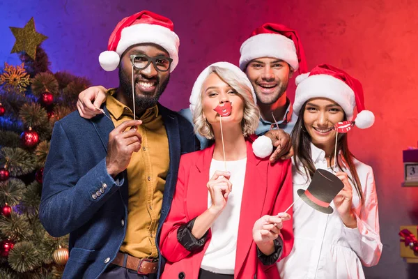 Multicultural businesspeople holding lips and glasses on sticks at new year corporate party — Stock Photo