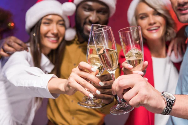 Selective focus of multicultural businesspeople clinking with glasses of champagne at new year corporate party — Stock Photo