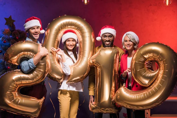 Multicultural businessmen and businesswomen holding 2019 balloons at new year corporate party — Stock Photo