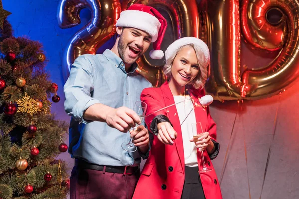 Gerentes jovens em chapéus santa segurando faíscas de Natal na festa corporativa do ano novo — Fotografia de Stock