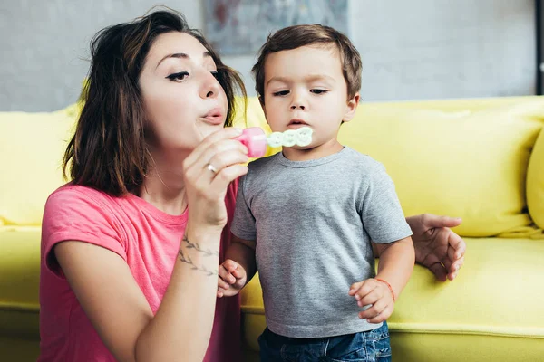 Glückliche Mutter und kleiner Sohn pusten zu Hause gemeinsam Seifenblasen — Stockfoto