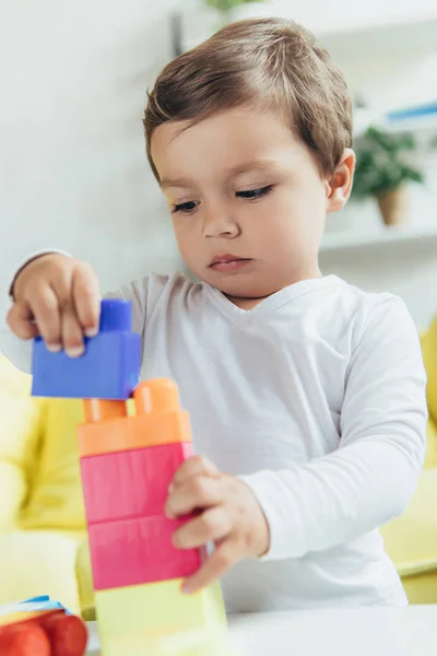 Tout-petit jouant avec des blocs de constructeur colorés à la maison — Photo de stock