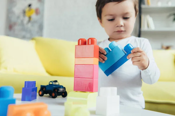 Niño masculino jugando con constructor colorido y coche de juguete en casa - foto de stock