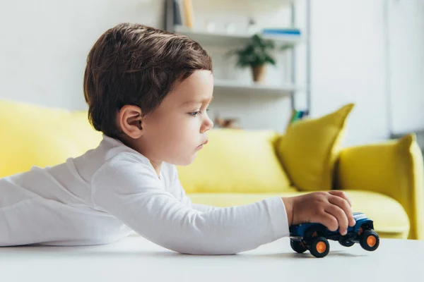 Adorable petit garçon jouant avec voiture jouet à la maison — Photo de stock