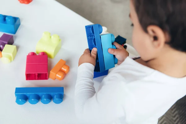 Recortado vista de niño jugando con bloques de constructor de colores - foto de stock