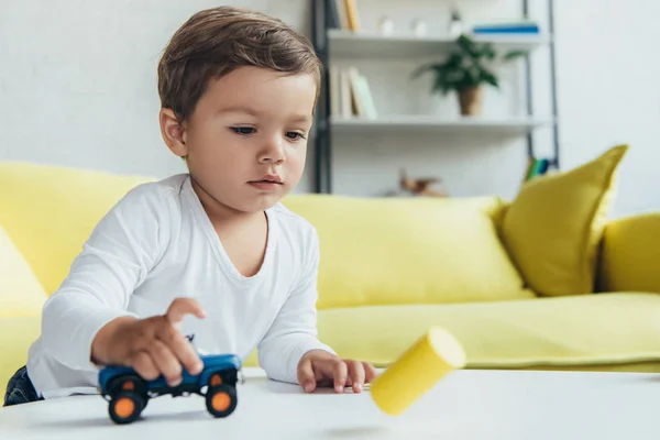 Criança adorável brincando com carro de brinquedo azul em casa — Fotografia de Stock