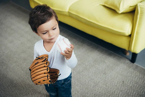 Entzückendes kleines Kind spielt zu Hause mit Baseballhandschuh und Ball — Stockfoto