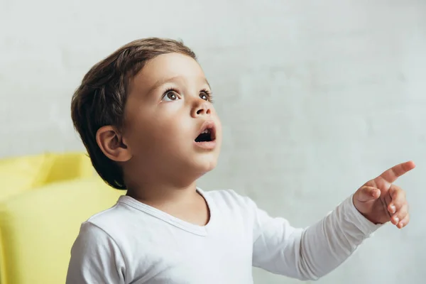 Portrait of little shocked boy pointing and looking up — Stock Photo