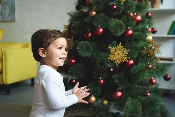 Adorable sonriente chico cerca de árbol de Navidad en casa - foto de stock