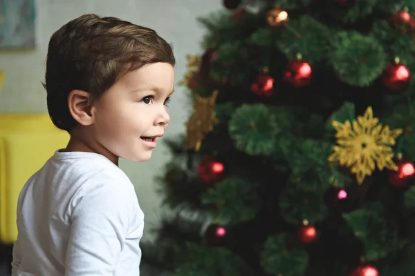 Glücklicher Junge steht neben Weihnachtsbaum zu Hause — Stockfoto