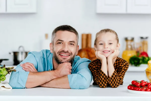 Father and adorable little daughter looking at camera on kitchen — Stock Photo