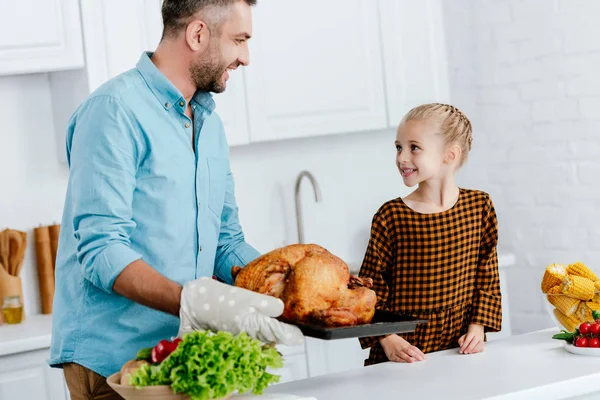 Father and adorable little daughter baking turkey for thanksgiving dinner — Stock Photo