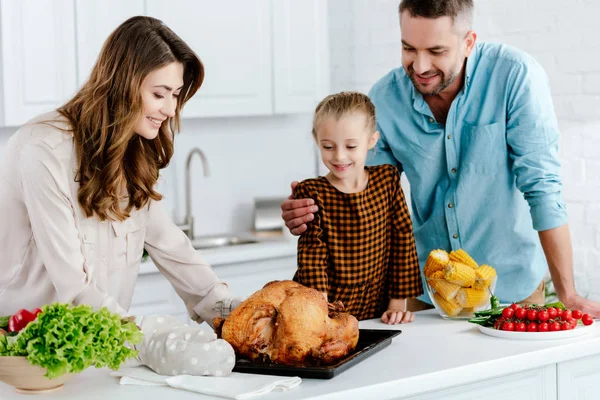 Parents and daughter looking at freshly baked thanksgiving turkey — Stock Photo