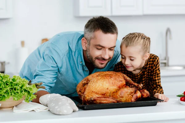 Happy father and daughter sniffing freshly baked thanksgiving turkey — Stock Photo
