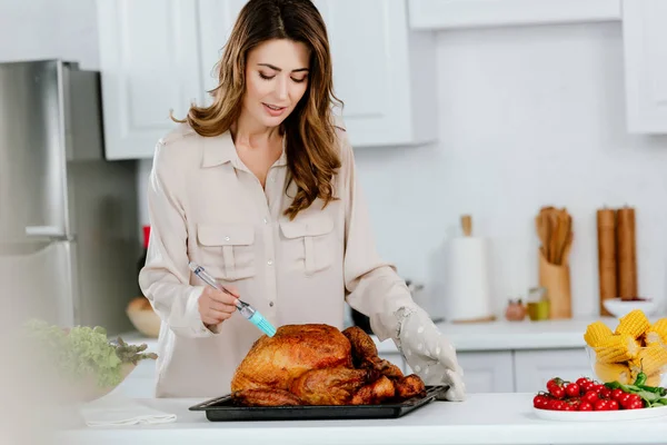 Attractive happy woman cooking thanksgiving turkey at kitchen — Stock Photo
