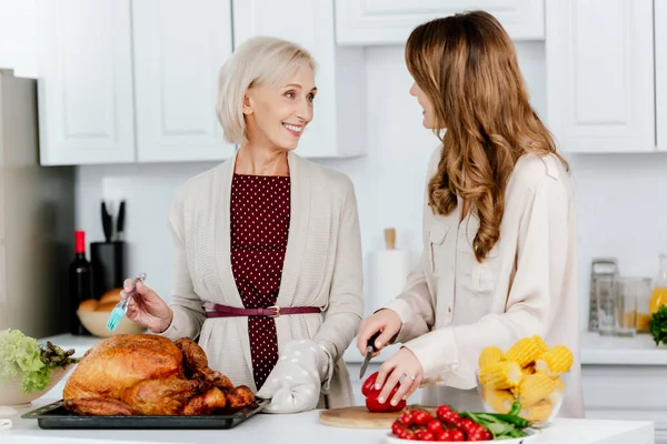 Atractiva hija adulta y madre mayor cocinando cena de acción de gracias juntos - foto de stock