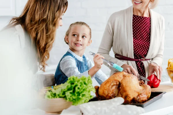 Beautiful mother and grandmother preparing thanksgiving turkey with granddaughter — Stock Photo
