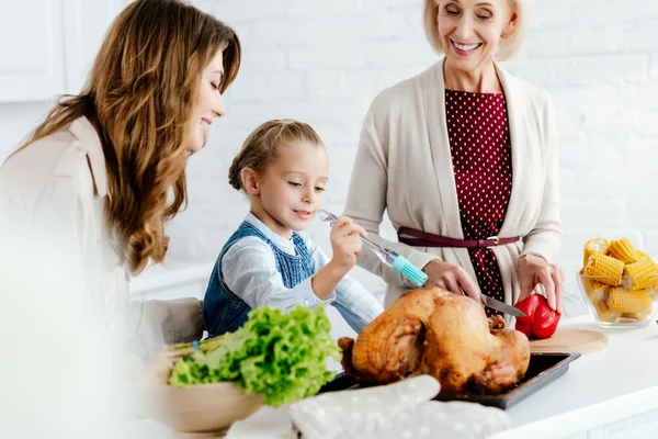 Mother and grandmother preparing thanksgiving turkey with granddaughter — Stock Photo
