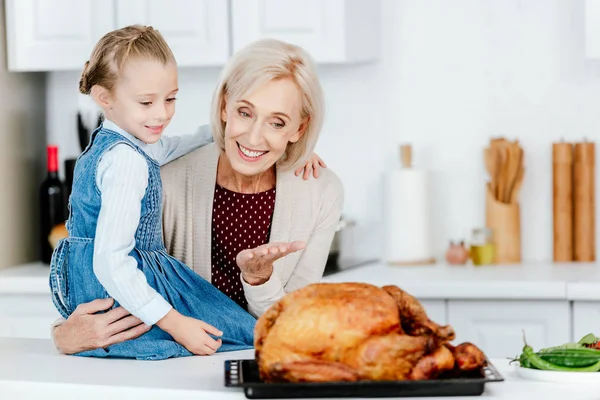 Feliz mujer madura preparando pavo de acción de gracias con nieta - foto de stock