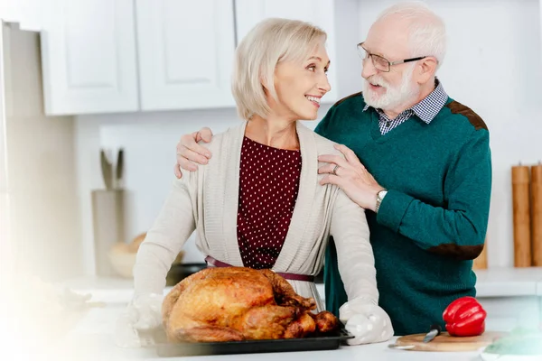 Любящая старшая пара готовит индейку на День Благодарения вместе — стоковое фото