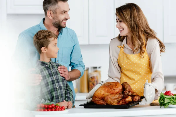 Adorabile bambino con i genitori preparare tacchino Ringraziamento insieme in cucina — Foto stock