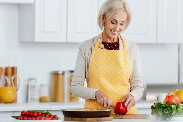 Felice donna anziana in grembiule cucina in cucina — Foto stock