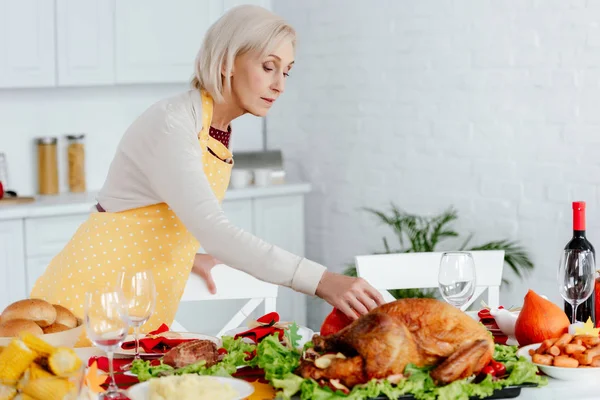 Belle table de service de femme âgée pour le dîner de thanksgiving dans la cuisine à la maison — Photo de stock