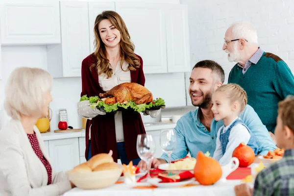 Hermosa mujer sonriente llevando pavo al horno para la cena de acción de gracias con la familia — Stock Photo