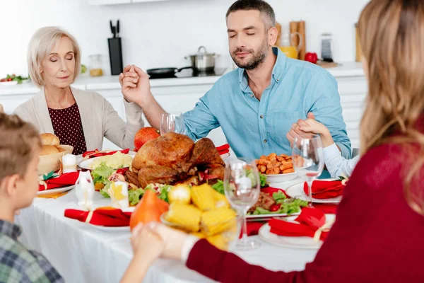 Happy family praying at served table with turkey before holiday dinner on thanksgiving — Stock Photo