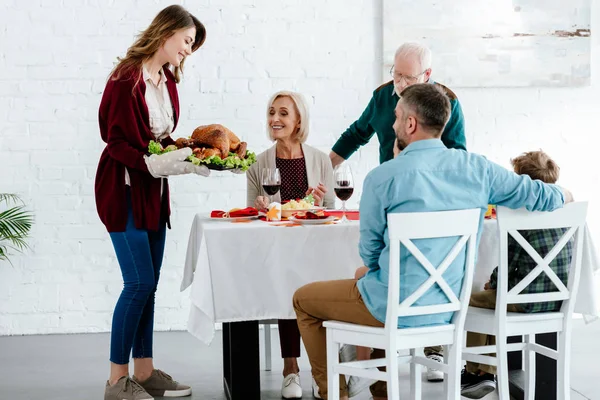 Hermosa mujer adulta llevando pavo al horno para la celebración de acción de gracias con la familia en casa - foto de stock