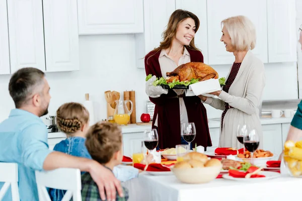 Senior woman carrying turkey with adult daughter for thanksgiving dinner with family at home — Stock Photo