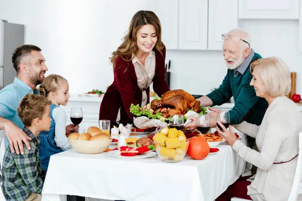 Mujer adulta y hombre mayor llevando pavo al horno para la cena de acción de gracias con la familia - foto de stock