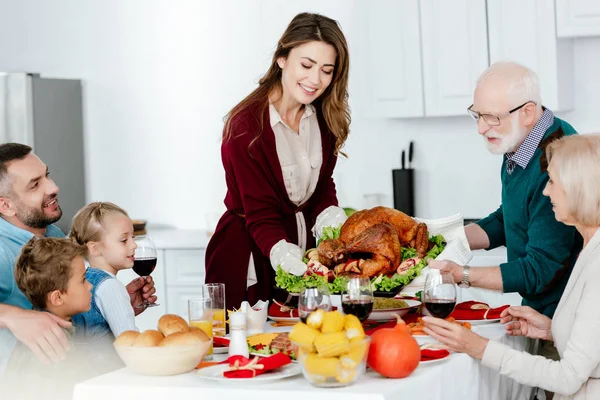 Дедушка и взрослая женщина несут запечённую индейку на ужин в честь Дня Благодарения с семьей — стоковое фото