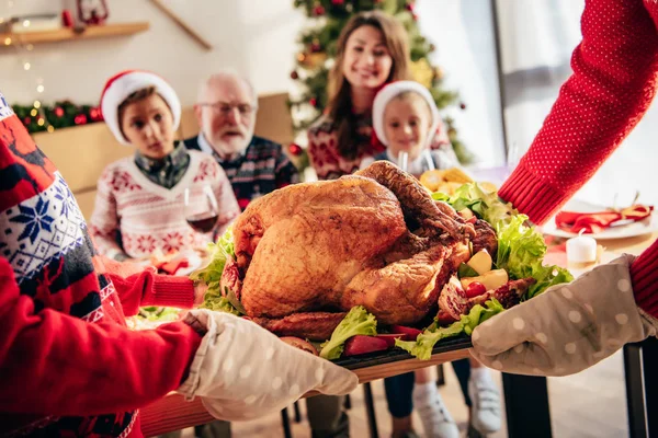 Обрезанный образ людей, несущих праздничную индейку на рождественский ужин с семьей дома — стоковое фото