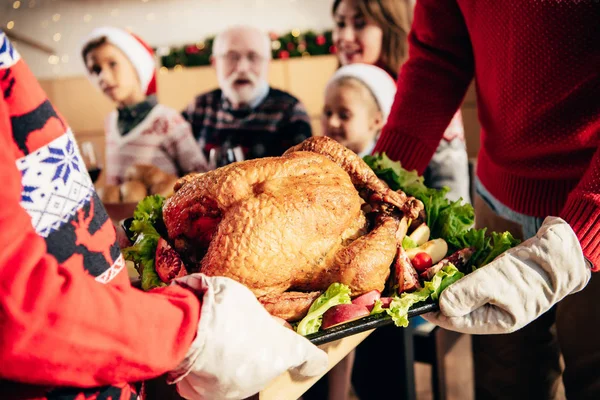 Cropped image of man and woman carrying turkey for christmas celebration with family at home — Stock Photo