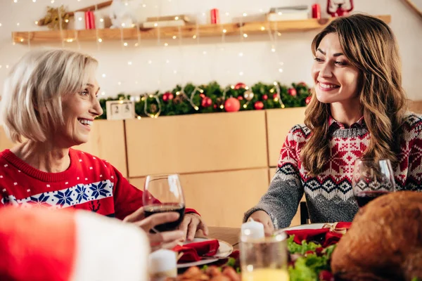 Senior lächelnde Frau mit Weinglas feiert Weihnachten mit erwachsener Tochter zu Hause — Stockfoto