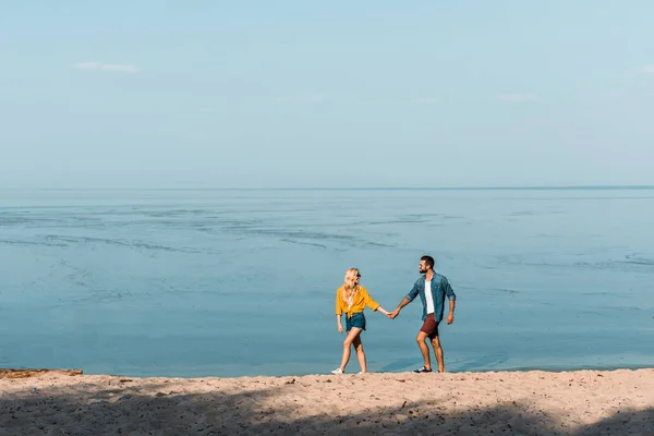 Пара тримає руки і ходить на пляжі — стокове фото