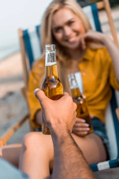 Imagen recortada de novio sosteniendo botella de vidrio de cerveza en la playa de arena - foto de stock