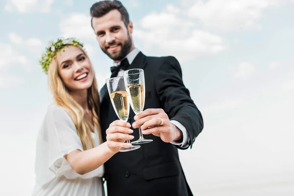 Selektiver Fokus des Hochzeitspaares, das am Strand mit Champagnergläsern klingelt — Stockfoto