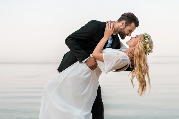 Cariñosa boda pareja va a besar en la playa - foto de stock