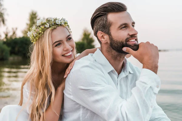 Portrait of smiling bride in wreath and handsome groom on beach — Stock Photo