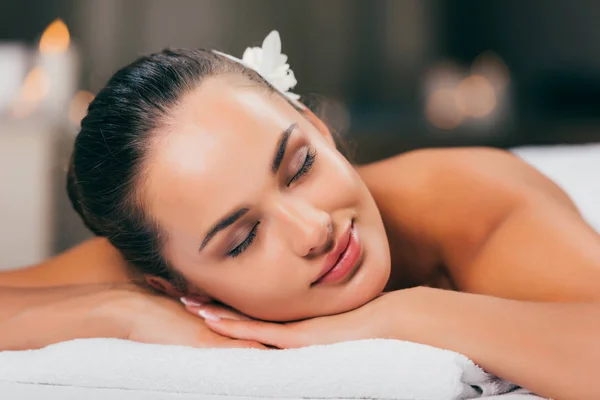 Mujer joven con flor en el pelo durmiendo en el salón de spa — Stock Photo