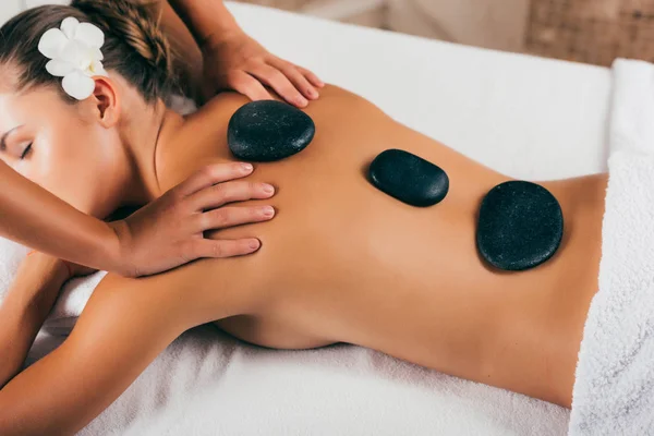 Hermosa joven que tiene terapia de piedra en el salón de spa — Stock Photo