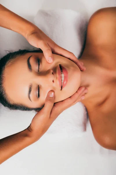 Smiling woman relaxing and having face massage in spa salon — Stock Photo