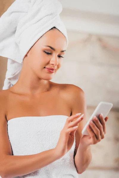 Atractiva mujer usando teléfono inteligente en el salón de spa - foto de stock