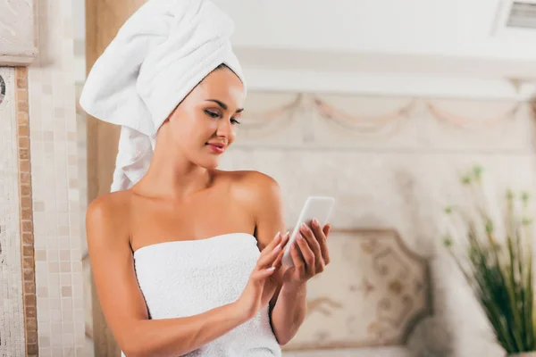 Belle femme en utilisant smartphone au salon de spa — Photo de stock