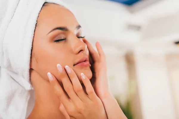 Attraente donna in asciugamano sulla testa toccare perfetto viso pulito — Foto stock