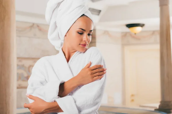 Jeune femme en peignoir éponge blanc avec serviette sur la tête — Photo de stock